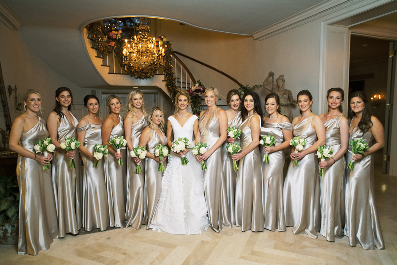 Bride surrounded by large bridal party in gold dresses