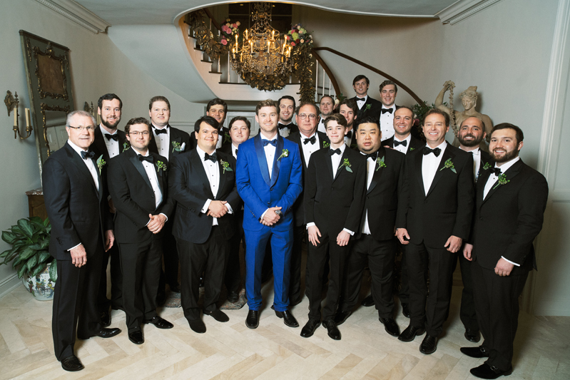 Groom in blue suit surrounded by groomsmen