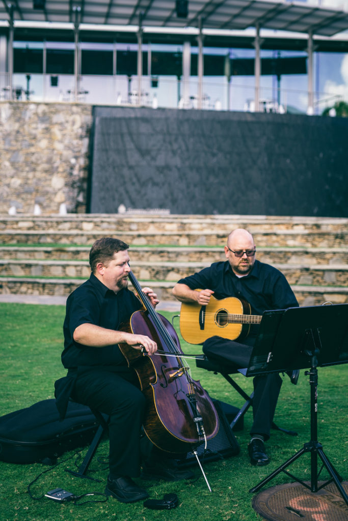 Cellist and guitarist duo playing during outside wedding ceremony