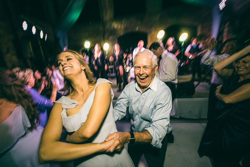 smiling couple dancing during wedding reception with wedding band in background