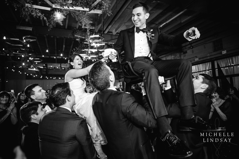 Bride and groom lifted in chairs during reception to sounds of Modern Luxe wedding band.
