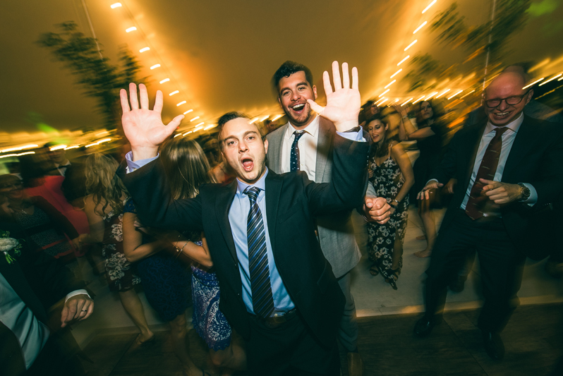 Man dancing with hands in the air during Summerfield Farms wedding reception.