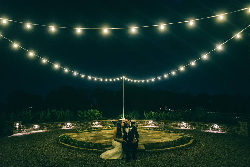 Bride and Groom kissing beneath string lights at Summerfield Farms wedding