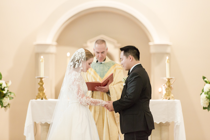Bride and groom saying vows in front of minister during church wedding.