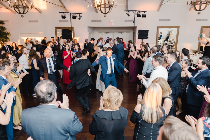 Crowded dance floor during wedding reception at Bride and groom dancing The Hora at Jewish wedding at Chesapeake Bay Beach Club.