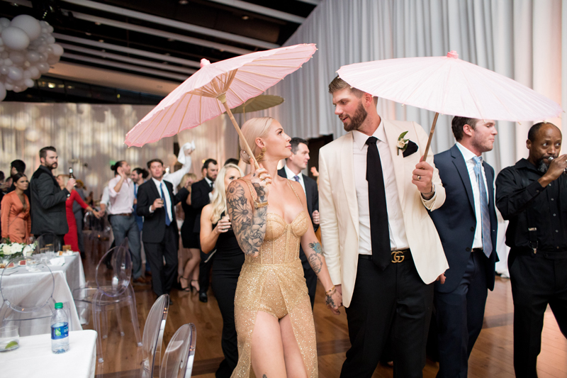 Bride and groom with pink and white parasols in Second Line at Nashville wedding.